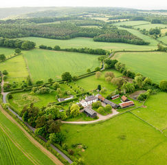 Aerial view of a large estate with house, gardens, outbuildings, and extensive land in the English countryside